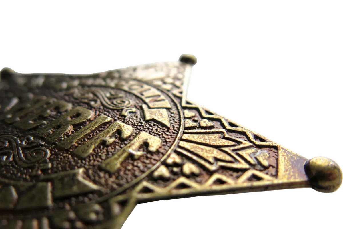 Denix 104 Lincoln County sheriff badge in antiqued brass, angled close-up of engraved edge and ball-tip point