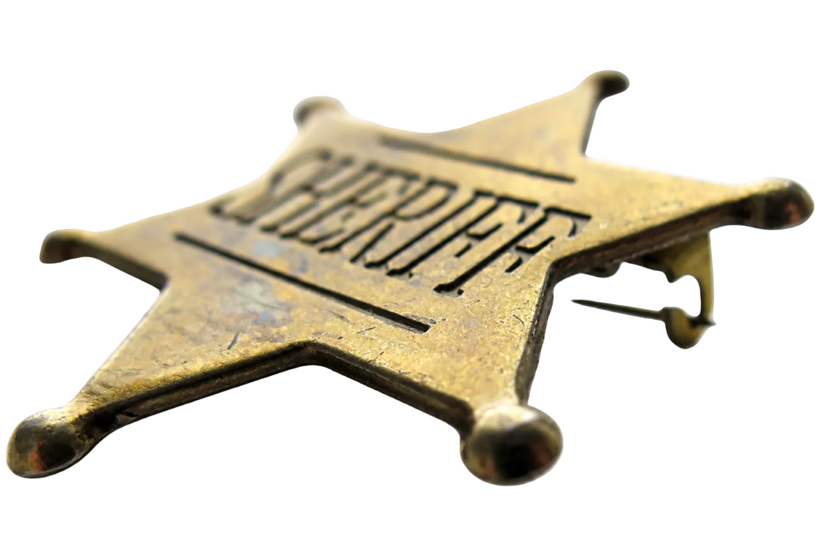 Denix 106 sheriff star badge in antiqued brass, low-angle front view with rear pin visible