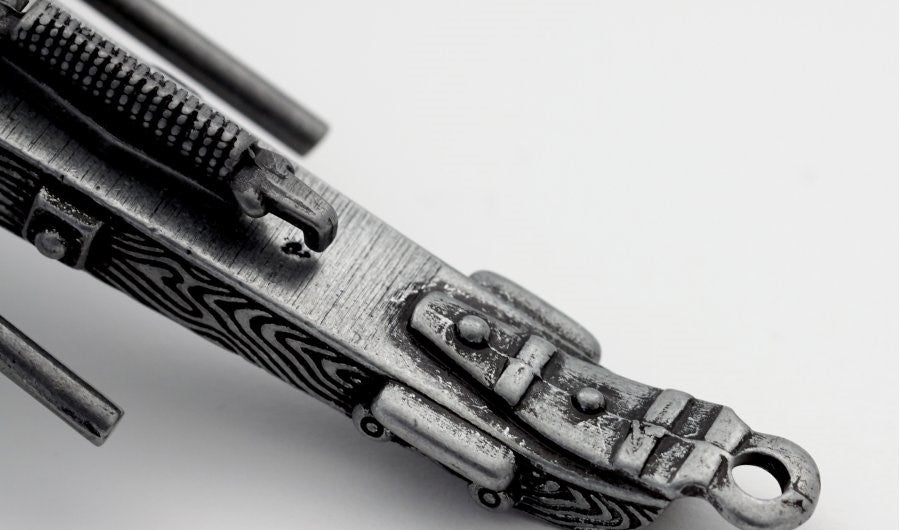 Close-up of a metallic object with intricate design on a light gray background