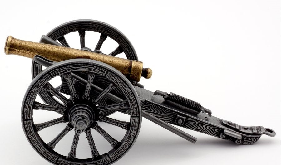 Model of a cannon with black wheels and gold barrel on a white background