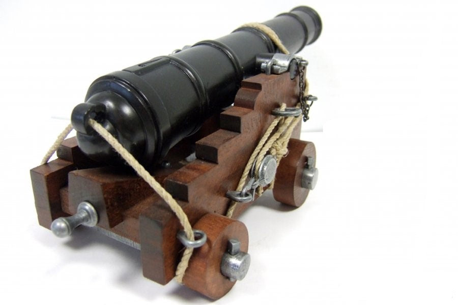 Model cannon on a wooden carriage with metal wheels against a white background